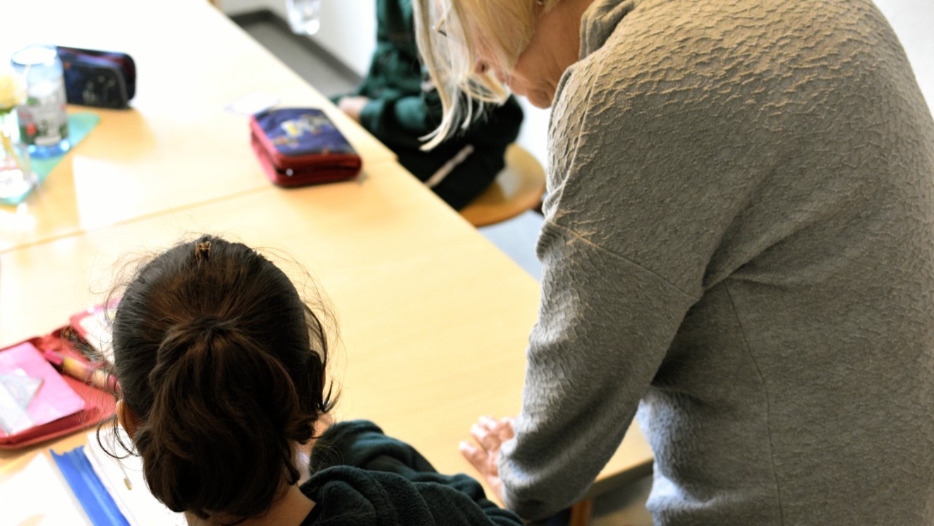 Hausaufgabenhelferin blickt Schülerin über die Schulter