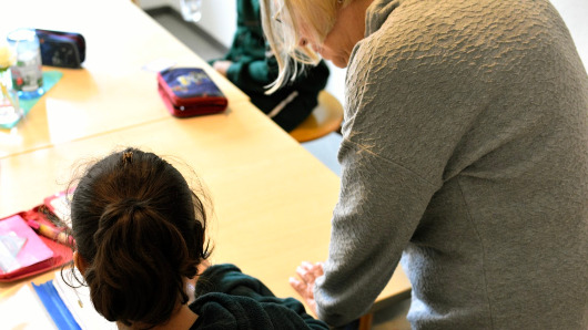 Hausaufgabenhelferin blickt Schülerin über die Schulter